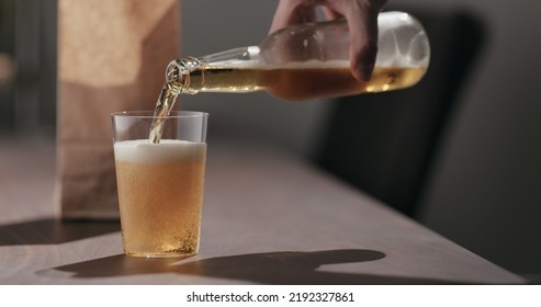 Man Pour Amber Color Fizzy Drink In Tumbler Glass With Bag Of Potato Chips On Background, Wide Photo