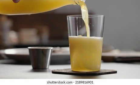 Man Pour Orange Soda Over Ice In Tumbler Glass To Make Spritz Drink On Concrete Countertop, Wide Photo