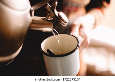 Man Pouring Boiling Water From Kettle In Mug Preparing Coffee Or Tea At Home