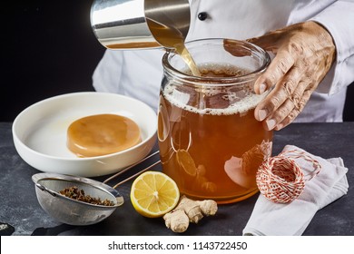 Man pouring a brew of sweetened black tea into a sterilised glass jar ready to add the scoby while making homemade kombucha