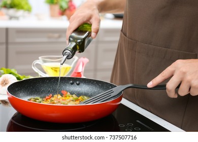 Man Pouring Cooking Oil From Bottle Into Frying Pan On Stove