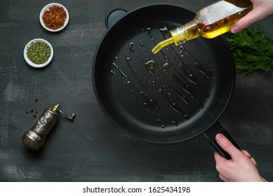 Man pouring cooking oil on the frying pan - Top View on a dark background