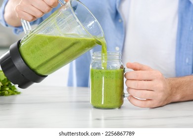 Man pouring delicious smoothie into glass at white marble table indoors, closeup - Powered by Shutterstock