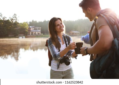 Man pouring drink into mug for young woman outdoors. Camping season - Shutterstock ID 1162523842
