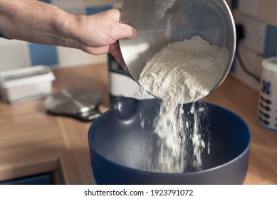 Man Pouring Flour Into A Blue Mixing Bowl.