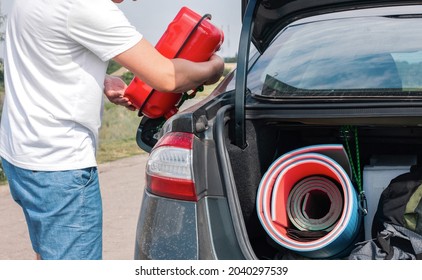 A Man Pouring Gasoline Into An Empty Fuel Tank From A Plastic Red  Gas Can. Filling  The Car From The Canister Into The Neck Of The Fuel Tank. 