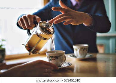 Man Pouring Herbal Tea In A Mug Of French Press.