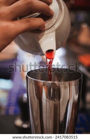 Man pouring hibiscus tea into a cocktail shaker to make an iced tea. Specialty cafeteria in Chile.