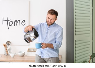 Man pouring hot boiled water from electric kettle into cup at home - Powered by Shutterstock