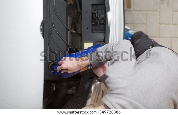 Man pouring motor oil into the engine of car.\
Repairing car by yourself with filling motor oil into the car\
engine. Changing oil.