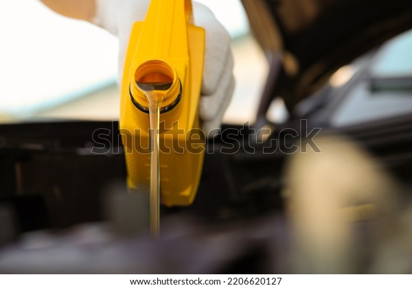 Man pouring motor oil from yellow container,\
closeup. Space for text