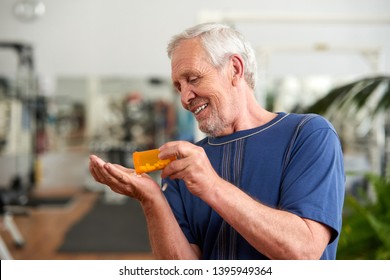 Man Pouring A Pill From Into Hand. Older Man Taking Daily Medicine To Consume. Sport Nutrition Concept.