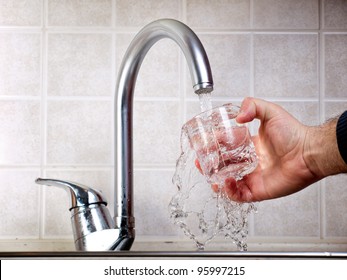 Man Is Pouring Potable Water From The Faucet In A Glass.