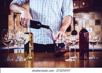 Man Pouring Red Wine From Bottle Into A Decanter, Home Kitchen Interior, Bottles Of Wine