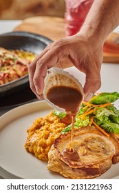 A Man Pouring Sauce On Pork Steak And Fresh Green Salad