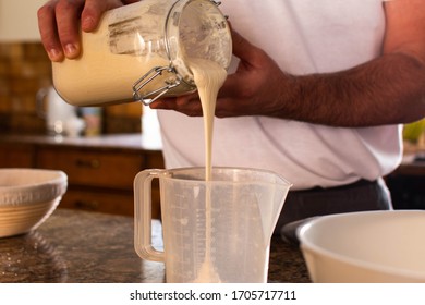 A Man Pouring Sour Dough Starter Into A Measuring Jug As Part Of A Sourdough Bread Making Recipe