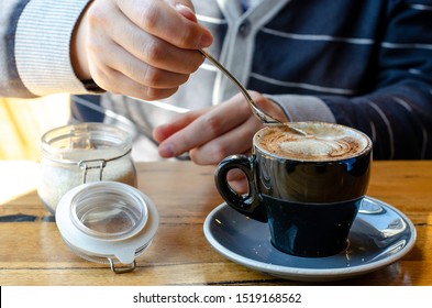 Man Pouring Sugar From Container In His Coffee.