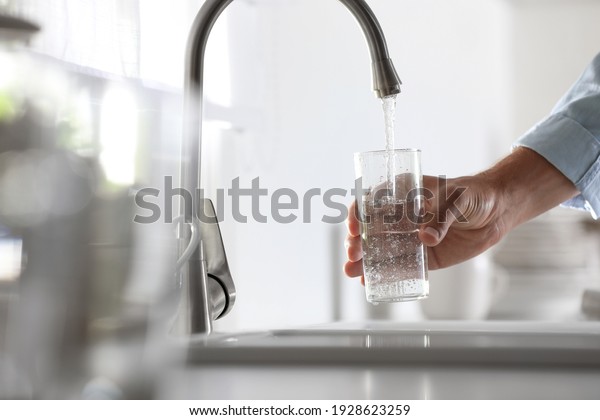 Man Pouring Water Into Glass In Kitchen Closeup 