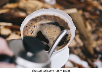 Man pouring water from the kettle into the coffee filter. Fresh morning pour over coffee blossoms in the dripper - Shutterstock ID 267418985