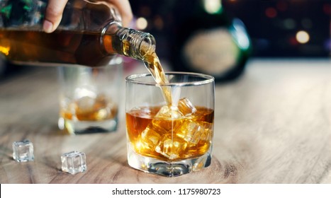 Man Pouring Whiskey In Glasses Of Whisky Drink Alcoholic Beverage With Friends At Bar Counter In The Pub.