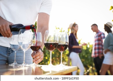 Man pouring wine from bottle into glasses at vineyard, closeup - Powered by Shutterstock