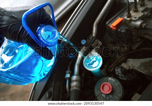 Man\
pouring winter windshield washer fluid. Pouring antifreeze liquid\
screen wash. Filling windscreen water tank with winter washer fluid\
concentrate. Antifreeze screen wash concentrate.\
