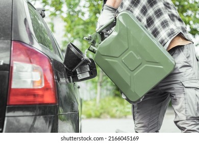 a man pours gasoline from a canister directly into the tank of a car. Green Jerrycan full of gas. Fuel shortage while travelling far.
