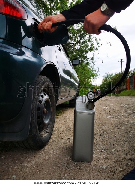 A man\
pours gasoline from a car tank into a canister. Lack of gasoline in\
Ukraine, lack of fuel in the car, and available at the gas station.\
Refueling. Fuel crisis in the\
country.