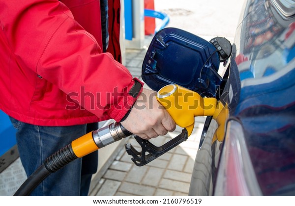 A man pours gasoline into the\
gas tank of a car at a gas station. Fuel for cars,\
transport.