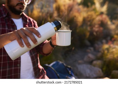 A Man Pours Hot Water From A Flask Into His Coffee Mug While Backpacking Camping