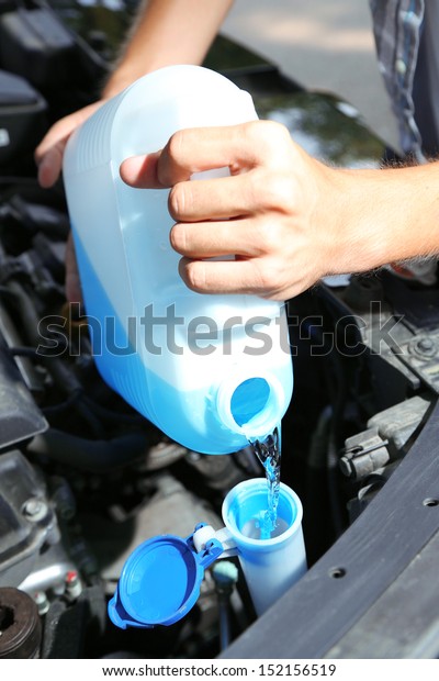 Man pours liquid\
for washing glasses to car