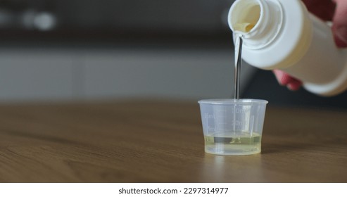 Man pours medical syrup into measuring cap. Medicine syrup bottle. Healthcare, people and Medicine concept. Close-up. - Powered by Shutterstock