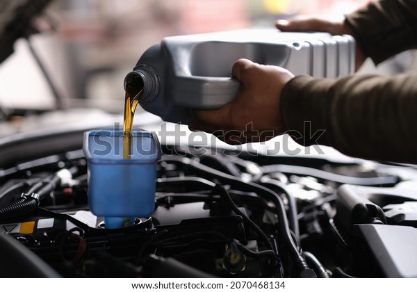 A man pours
oil into the car from a
canister