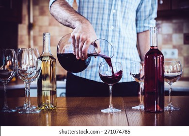 A Man Pours Red Wine From The Decanter Into A Glass, Home Kitchen Interior