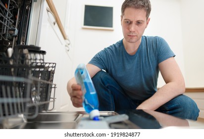 Man Pours Rinse Aid Into The Dishwasher Compartment.