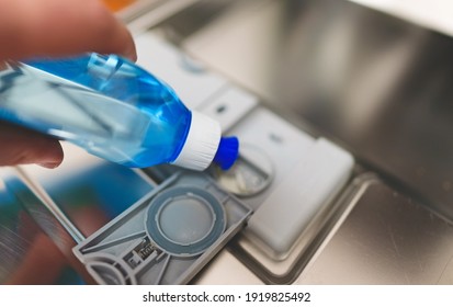 Man Pours Rinse Aid Into The Dishwasher Compartment.