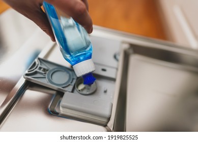 Man Pours Rinse Aid Into The Dishwasher Compartment.