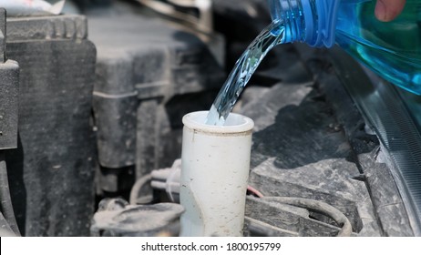 Man Pours Special Cleaning Solution Bottle Into A Car Window Washer Tank