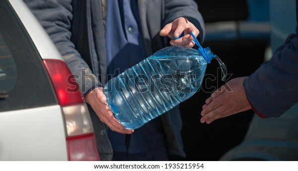 \
a man pours water from a plastic bottle onto\
another man\'s hands