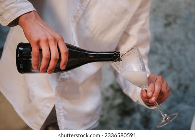 Man pours wine into glasses. The waiter pours prosecco or sparkling champagne. Valentine's day in restaurant. Luxury romantic date. Engagement. Location for surprise marriage proposal. Closeup.