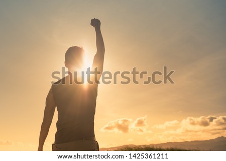 Man, power, victory, winning, hero concept. Strong young muscular male with fist in the air.