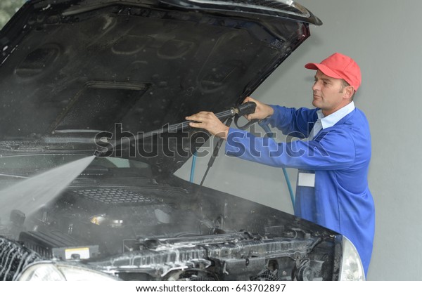 Man power washing\
automobile engine bay