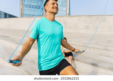 Man practices skipping rope exercise outdoors in bright sunlight near modern building