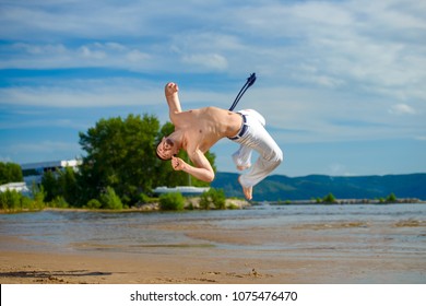 Man practicing capoeira on the beach - concept about people, lifestyle and sport. The man does the fighting element of capoeira.