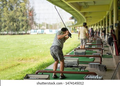 Man Practicing His Golf Swing At Golf Driving Range