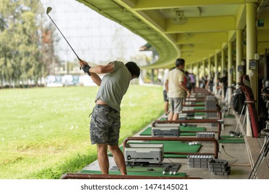 Man Practicing His Golf Swing At Golf Driving Range