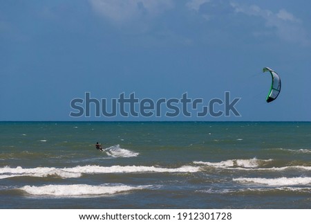 Man practicing kite surfing near  Forte Beach in Mata de São João in Bahia - Brazil. Strong wind, sea and sky with different shades of blue and the horizon line on a sunny day.