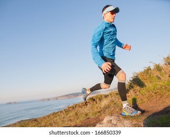 Man practicing trail running with a coastal landscape in the background - Powered by Shutterstock