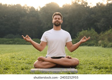 Man practicing yoga on mat outdoors. Lotus pose - Powered by Shutterstock