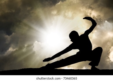 Man Practises Martial Arts with Dramatic Cloudy Sky in Background - Powered by Shutterstock